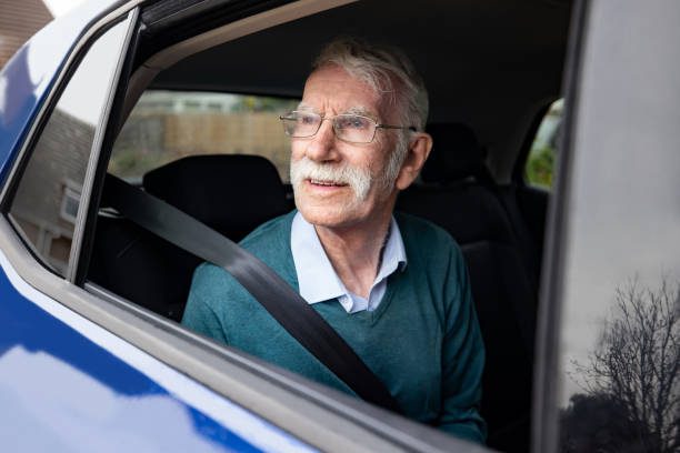 Portrait of an English senior man riding on the back seat of a car and looking out of the window